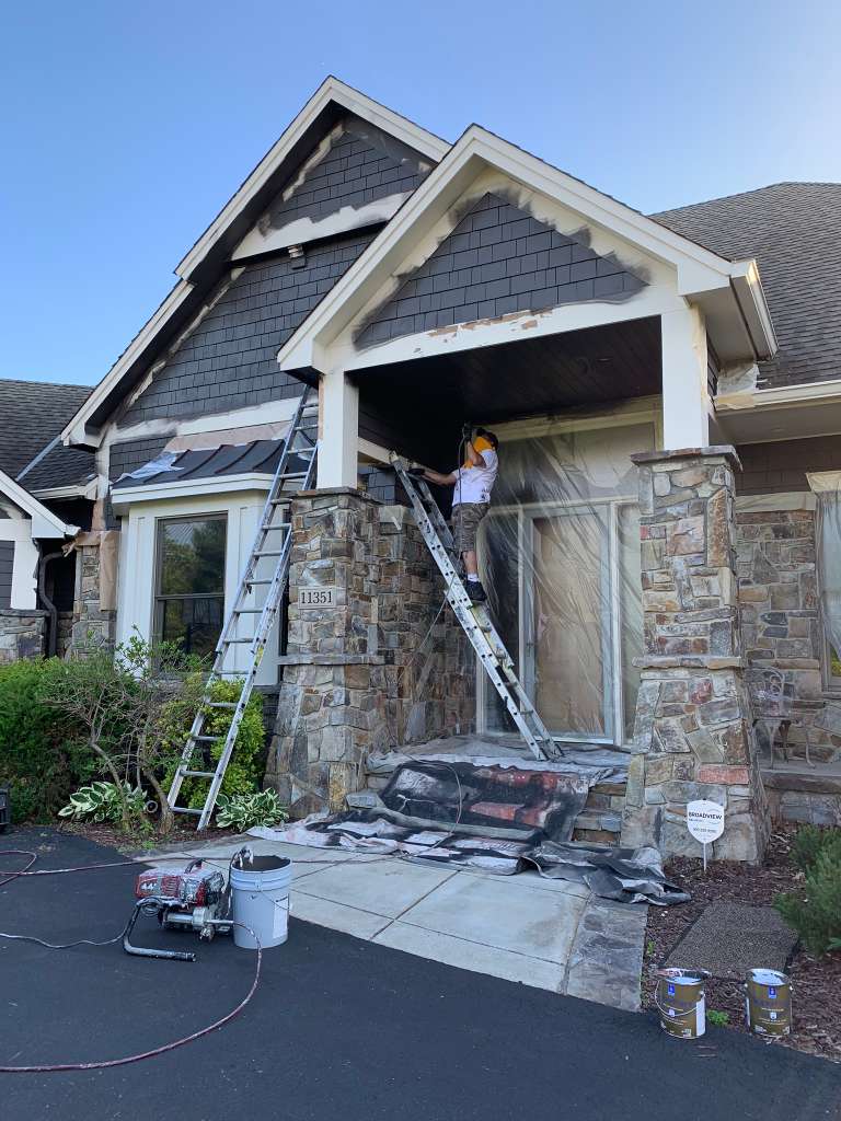 Team painting stone and siding home